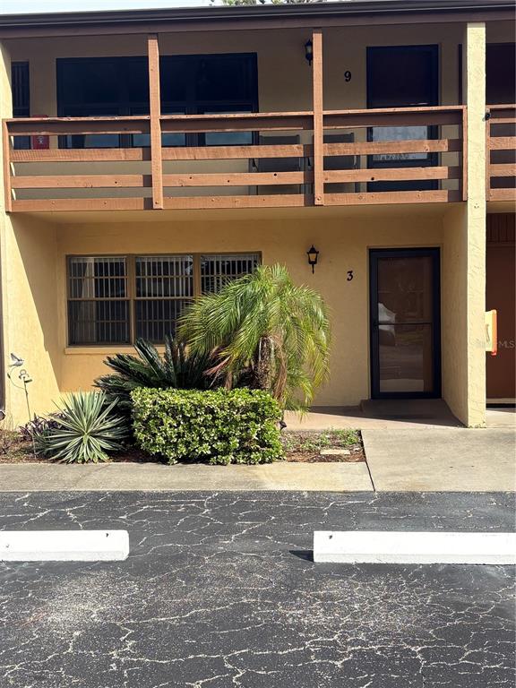 A two-story building exterior features a ground-level unit with a patio, landscaping, and parking — 9 QUAILS RUN BOULEVARD UNIT 3, ENGLEWOOD, FL