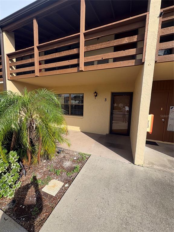 The exterior of a two-story residential building features a ground-level entrance and a wooden balcony — 9 QUAILS RUN BOULEVARD UNIT 3, ENGLEWOOD, FL