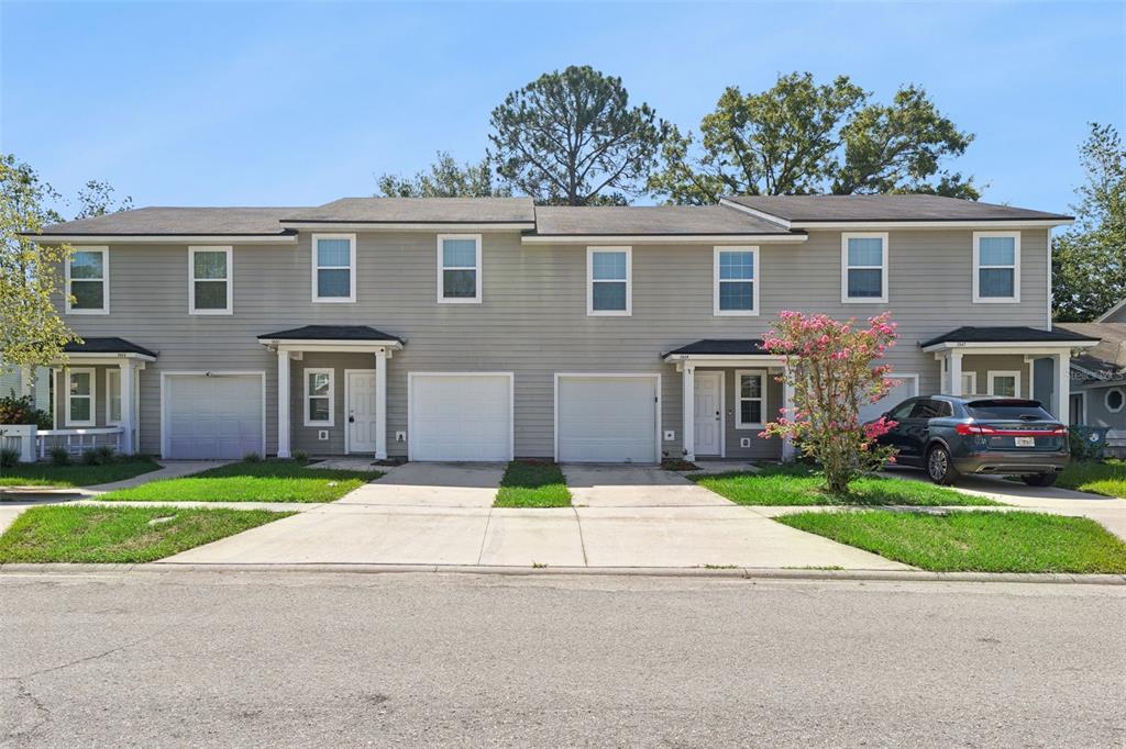 A row of two-story townhomes with gray siding, attached garages, and concrete driveways — 3551 RAIN FOREST DRIVE W, JACKSONVILLE, FL