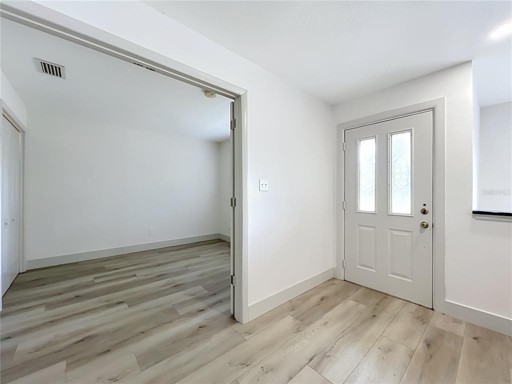 An entryway with light wood-look flooring leads into an adjacent room through an open doorway — 644 VISCAYA AVENUE, ORLANDO, FL