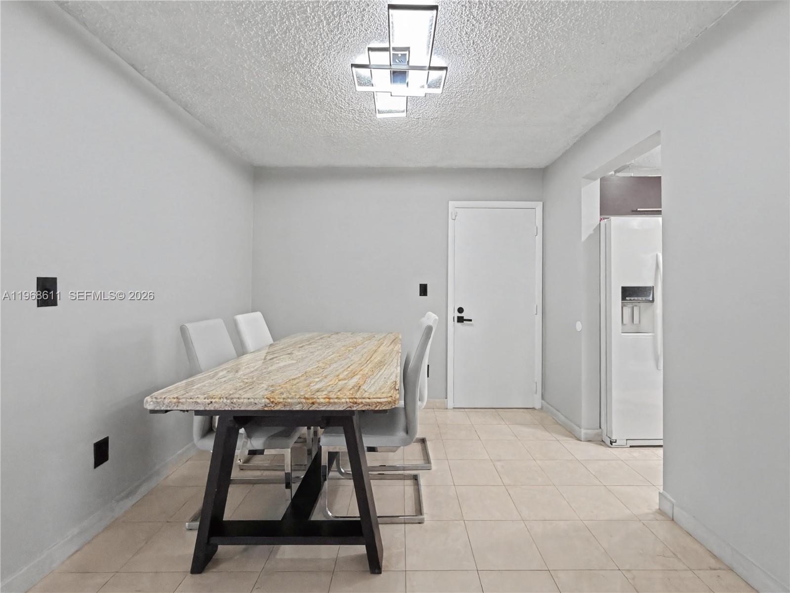 A dining room features a stone-topped table, modern chairs, tile flooring, and a geometric light — 10491 SW 122nd Ct, Miami FL 33186, MIAMI, FL