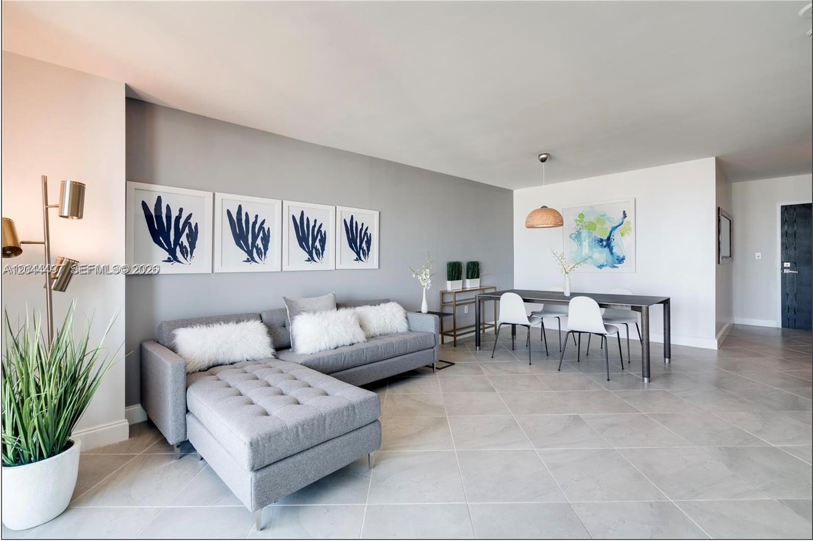 A living and dining area features a gray sectional sofa, four framed prints, and tile flooring — 90 Alton Rd # 1207, Miami Beach FL 33139, MIAMI BEACH, FL