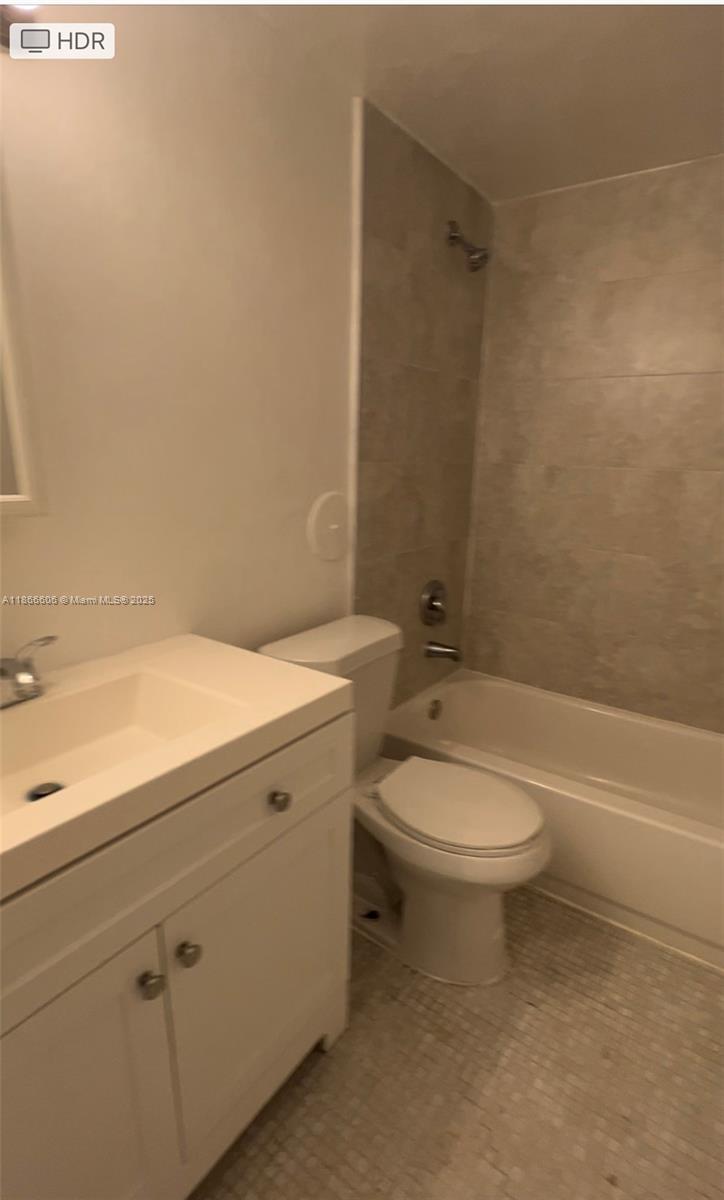 A bathroom features a white vanity, a toilet, and a shower-tub combination with tiled walls — 498 NW 165th St Rd # 101, Miami FL 33169, MIAMI, FL