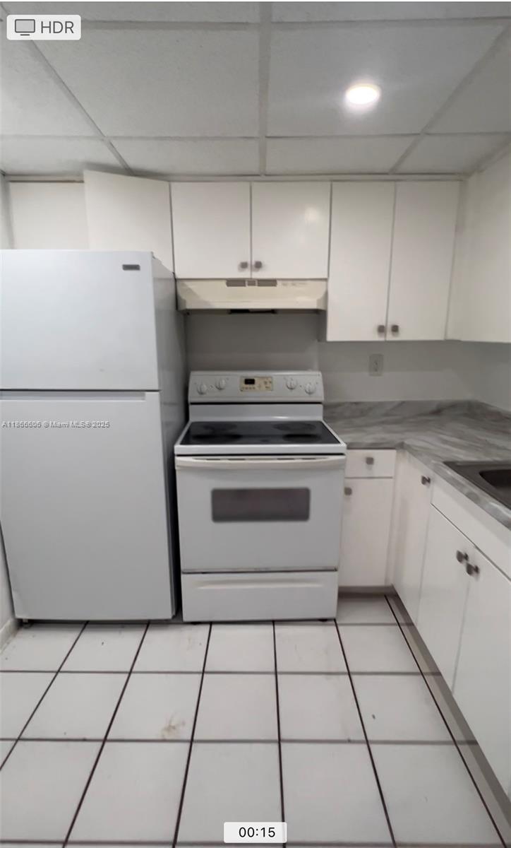 A kitchen features white cabinets, a white refrigerator, a white electric stove, and tiled flooring — 498 NW 165th St Rd # 101, Miami FL 33169, MIAMI, FL