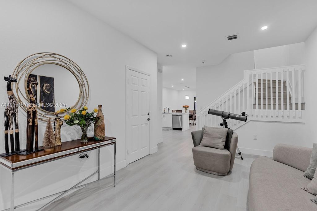 A bright living area features a console table, a telescope, and a staircase — 10254 SW 228th Terrace, Miami FL 33190, MIAMI, FL