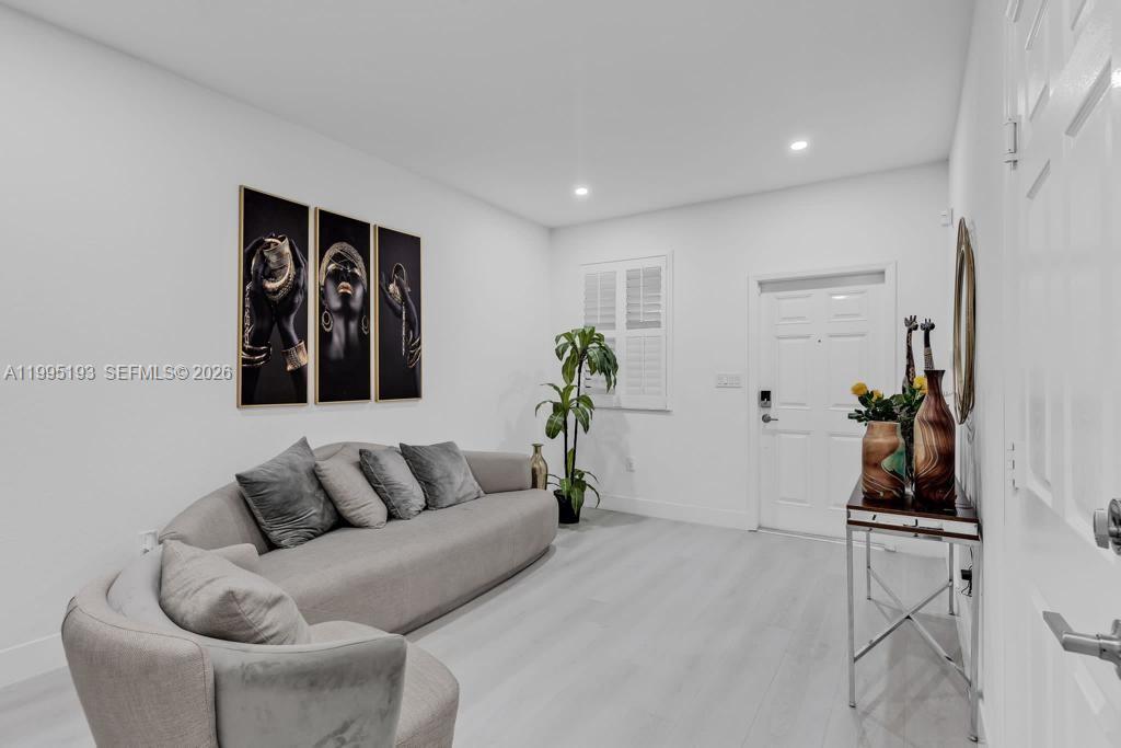 A living room features a gray sofa, a console table, and wall art on white walls — 10254 SW 228th Terrace, Miami FL 33190, MIAMI, FL