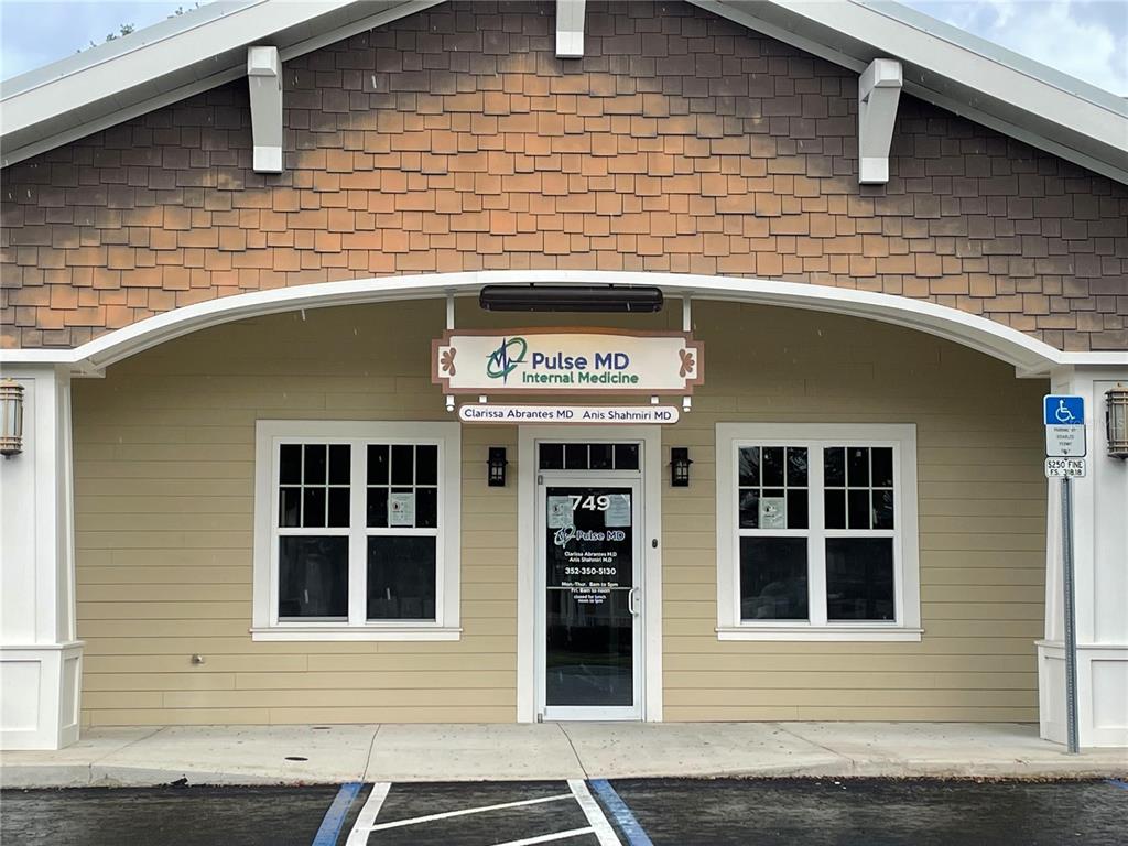 The exterior of a medical office building features tan siding, a shingled gable, and signage — 749 COUNTY ROAD 466, LADY LAKE, FL