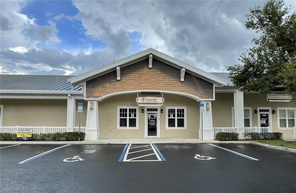 A single-story commercial building features a tan facade, a gabled roof, and two handicap parking spaces — 749 COUNTY ROAD 466, LADY LAKE, FL
