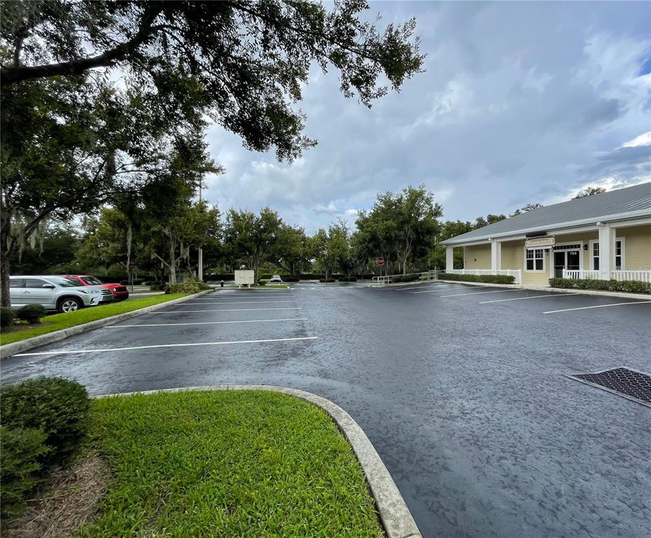 An asphalt parking lot sits in front of a single-story commercial building with trees — 749 COUNTY ROAD 466, LADY LAKE, FL