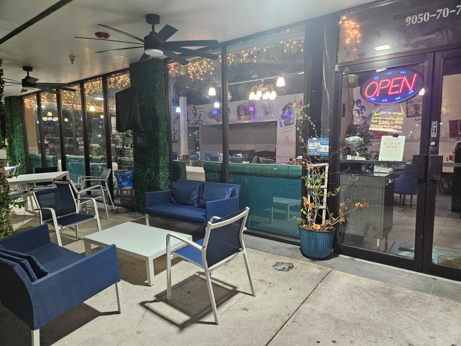 A restaurant patio features blue outdoor furniture, white tables, and a glass storefront entrance — 9050 Kimberly Boulevard # 71, Boca Raton FL 33434, BOCA RATON, FL