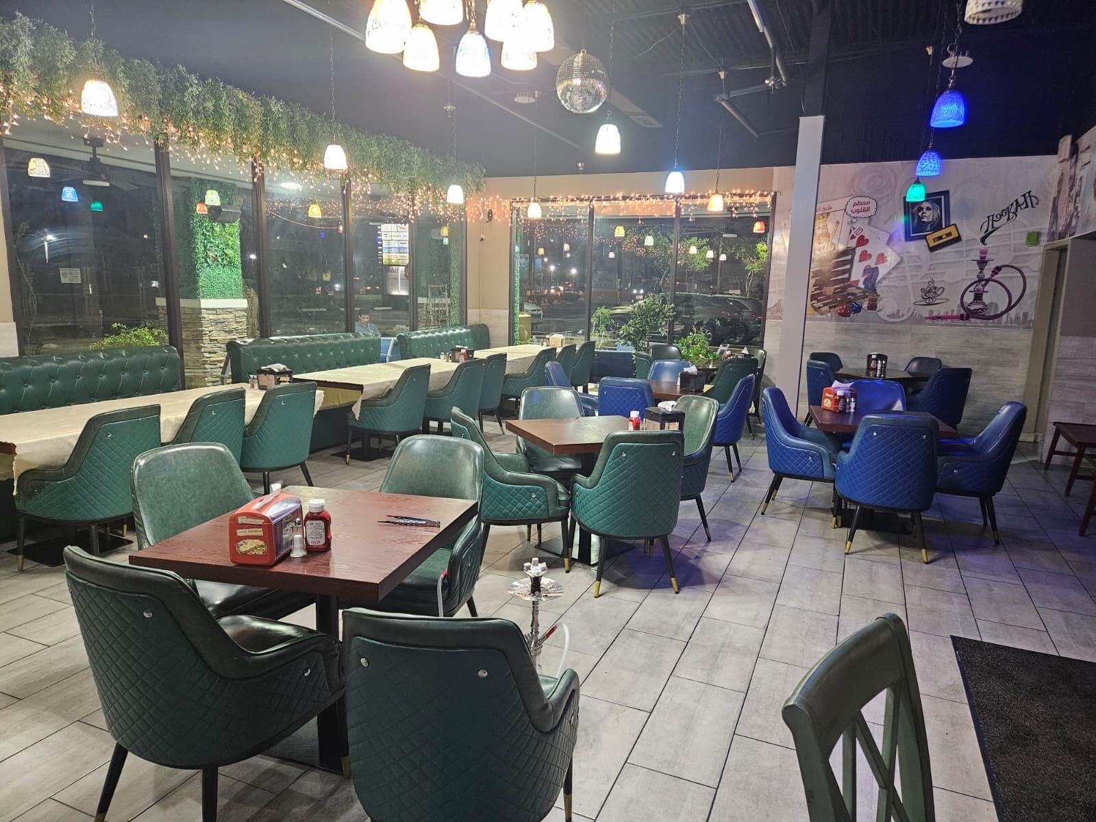 A restaurant interior featuring green and blue upholstered chairs, wooden tables, and decorative string lights — 9050 Kimberly Boulevard # 71, Boca Raton FL 33434, BOCA RATON, FL