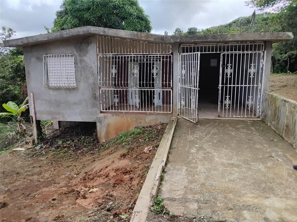 A small, unfinished concrete house with security bars on the windows and front entrance — BO.  INDIERA BAJA, MARICAO, PR