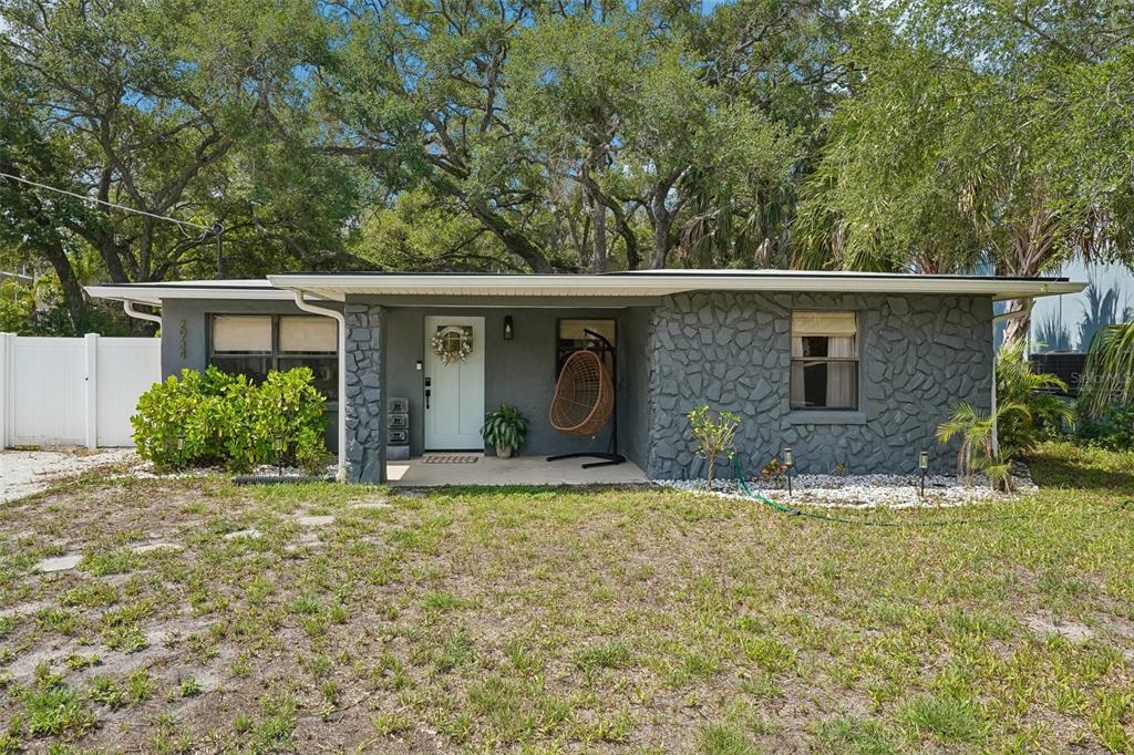 A single-story house with gray stone siding, a white front door, and a hanging chair — 2934 W ELLIS DRIVE, TAMPA, FL