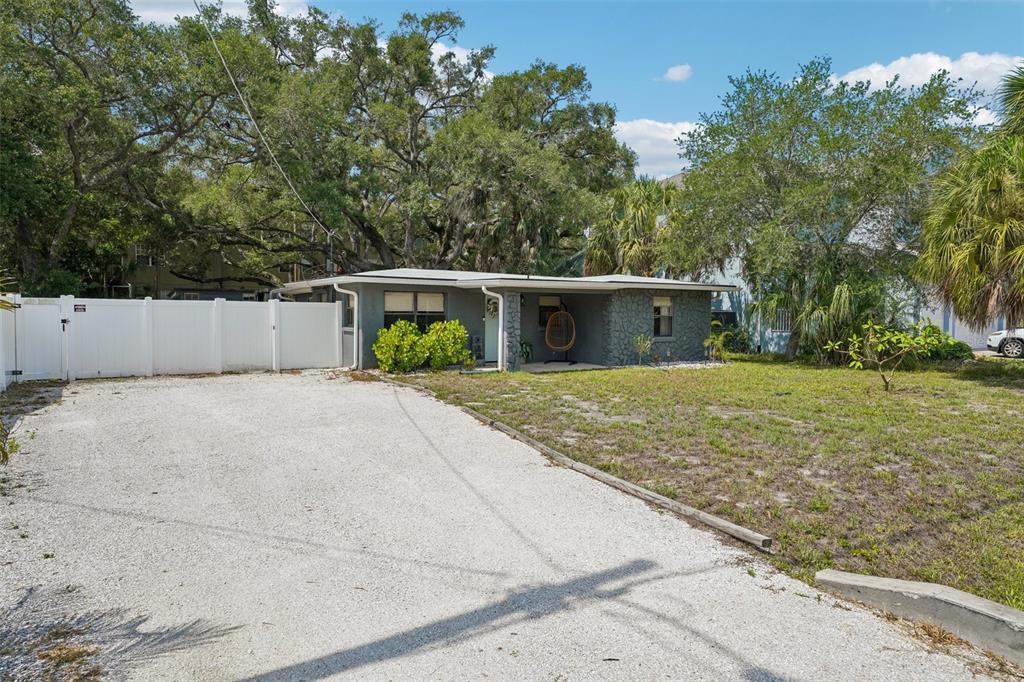 A single-story gray house with a gravel driveway and a white vinyl fence — 2934 W ELLIS DRIVE, TAMPA, FL