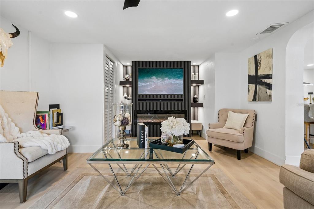 A living room features a slatted accent wall with a fireplace, television, and neutral furniture — 2934 W ELLIS DRIVE, TAMPA, FL