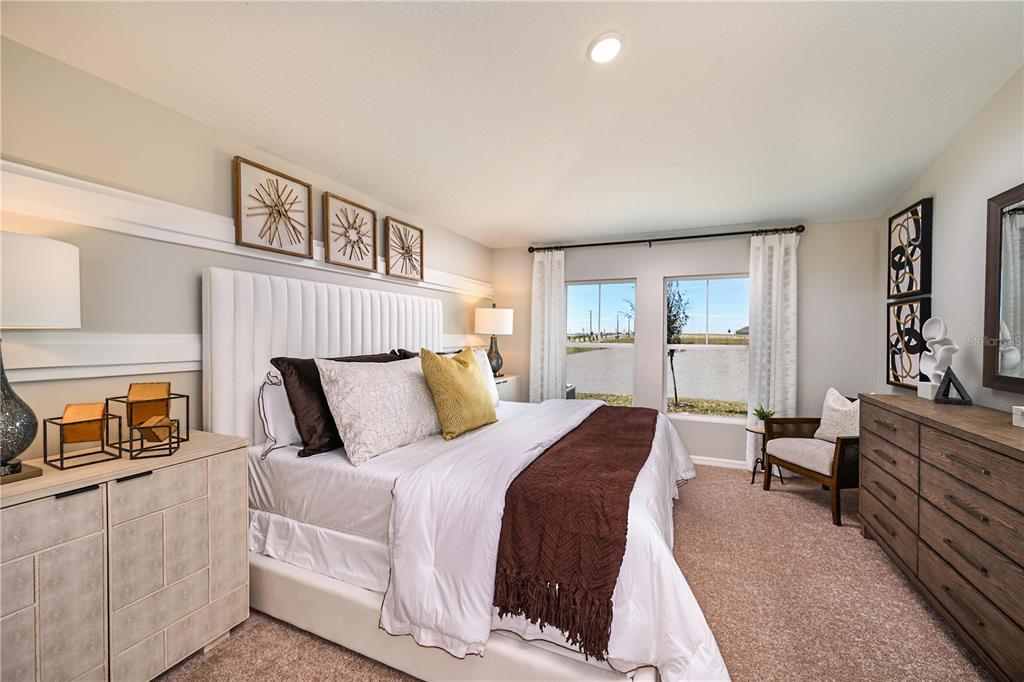 A bedroom features a white upholstered headboard, a dark brown throw, and two large windows — 31714 OYSTER TRELLIS LANE, WESLEY CHAPEL, FL