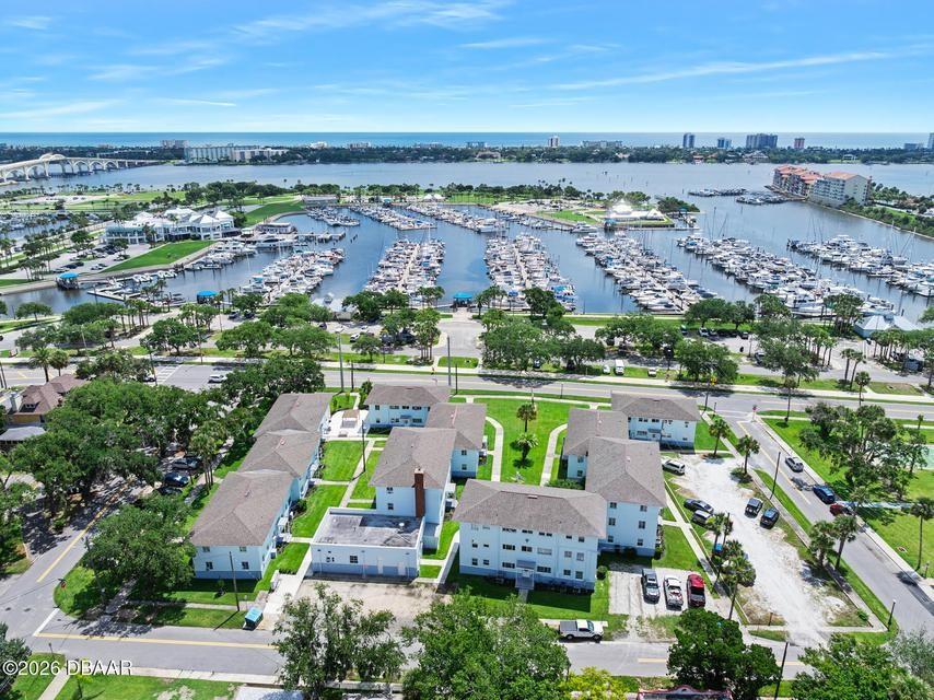 An aerial view shows a multi-building apartment complex situated near a large boat marina — 500 S BEACH STREET UNIT H2, DAYTONA BEACH, FL