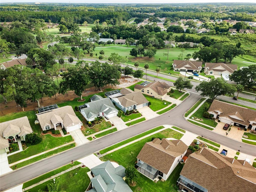 An aerial view of a suburban neighborhood featuring single-family homes, green lawns, and a golf course — 6240 FAIRSKIES DRIVE, NEW PORT RICHEY, FL