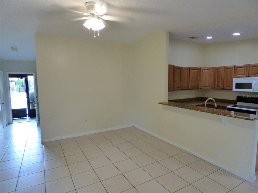 A kitchen with wood cabinets and a breakfast bar overlooks a tiled dining area — 3122 LORRY LANE, ORLANDO, FL