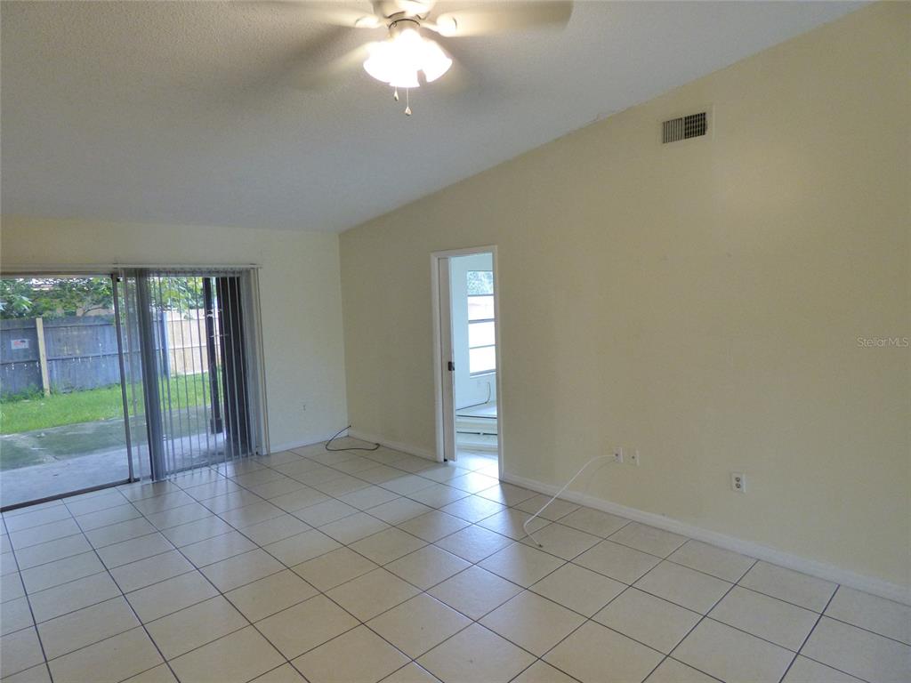 An empty room with light-colored tile flooring, a ceiling fan, and a sliding glass door — 3122 LORRY LANE, ORLANDO, FL