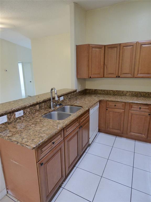 A kitchen features wood cabinets, granite countertops, a double sink, and white tile flooring — 3122 LORRY LANE, ORLANDO, FL