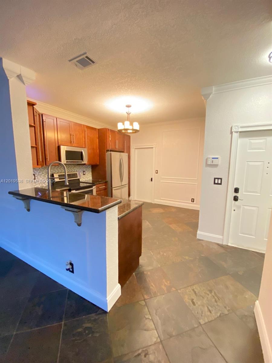 A kitchen features wooden cabinets, granite countertops, a breakfast bar, and dark tile flooring — 2041 Pompeii Ct # 2014, Weston FL 33327, WESTON, FL