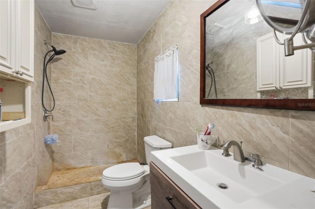 A bathroom features a walk-in shower, a toilet, and a vanity with a white sink — 13379 CHAMBORD STREET, BROOKSVILLE, FL