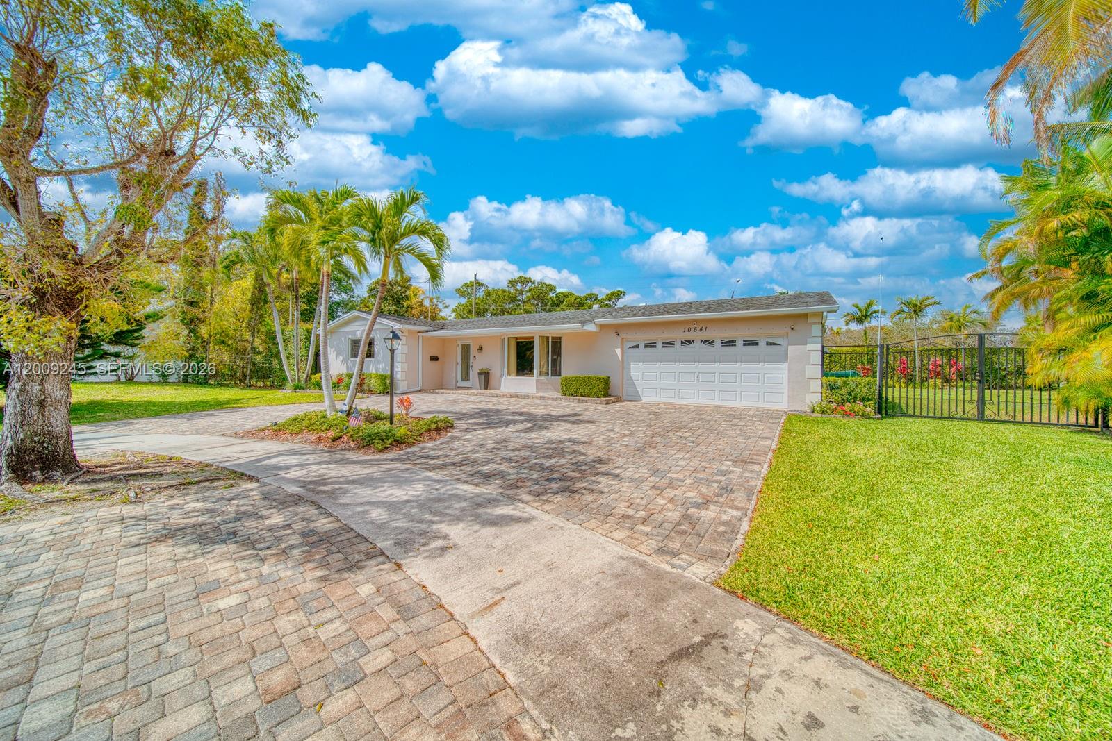 A single-story house with a paved driveway, a two-car garage, and surrounding palm trees — 10641 SW 99th Ter, Miami FL 33176, MIAMI, FL