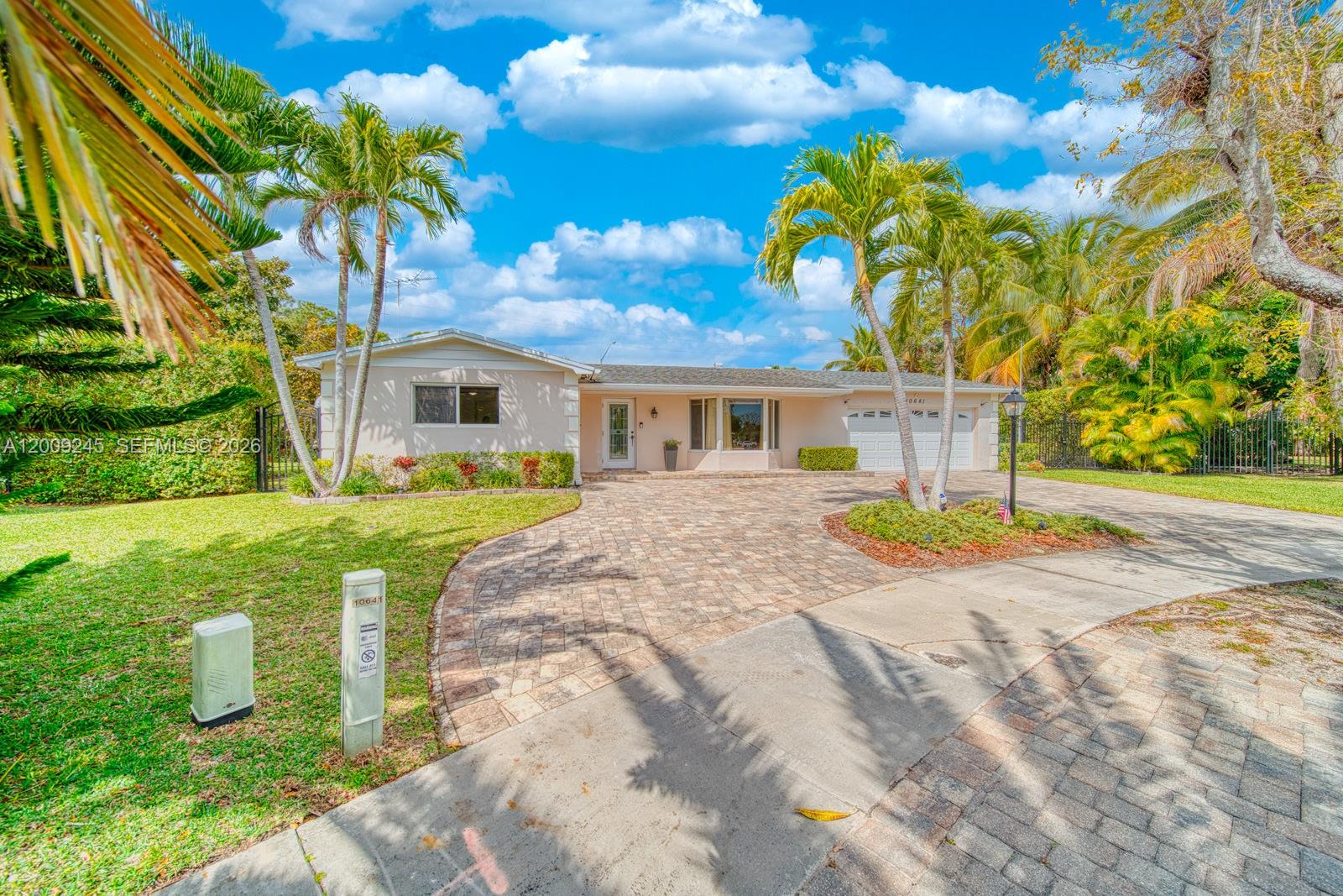 A single-story house with a paved driveway, palm trees, and a green lawn — 10641 SW 99th Ter, Miami FL 33176, MIAMI, FL