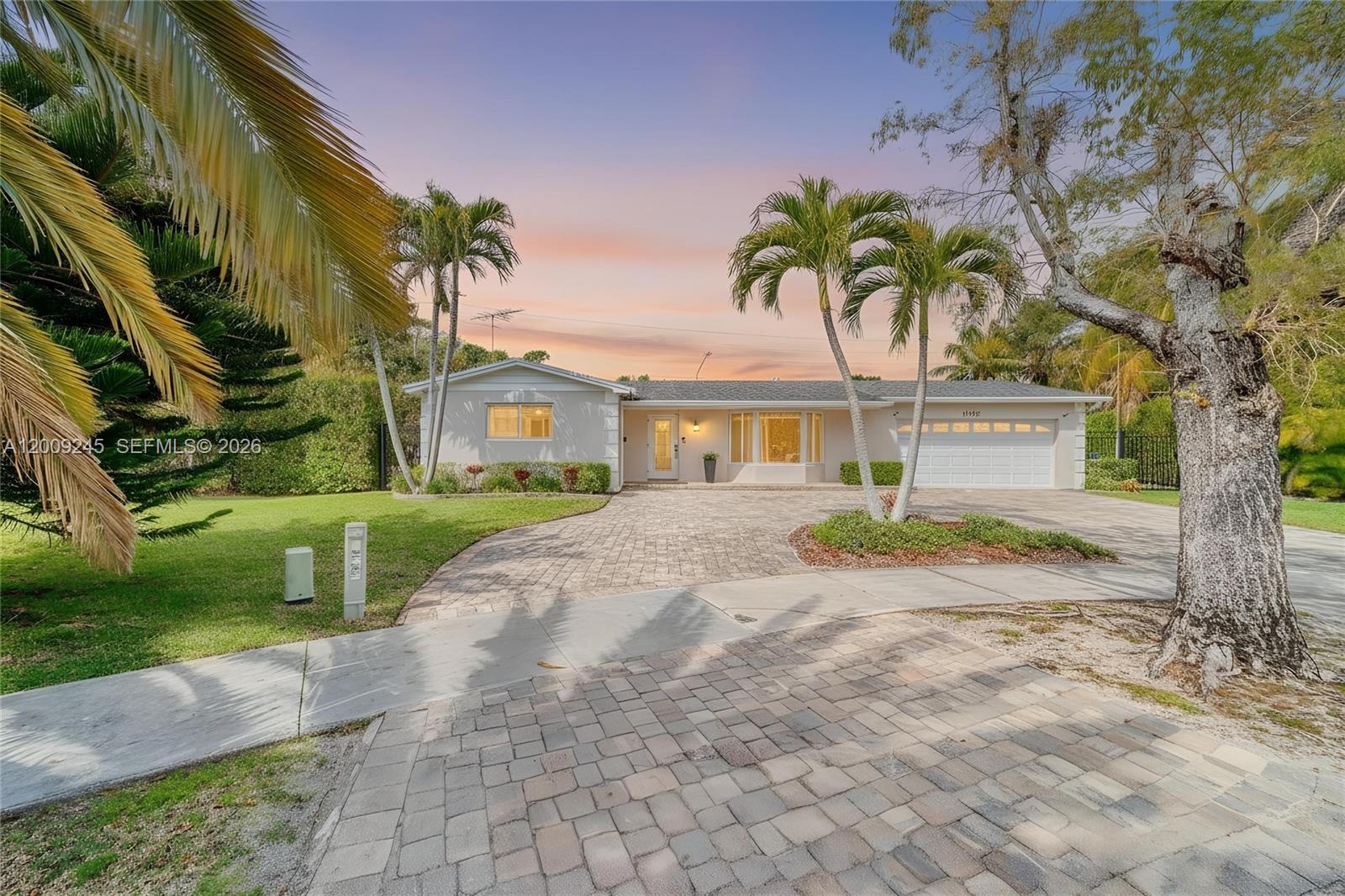 A single-story house with a paved driveway, palm trees, and a two-car garage at sunset — 10641 SW 99th Ter, Miami FL 33176, MIAMI, FL