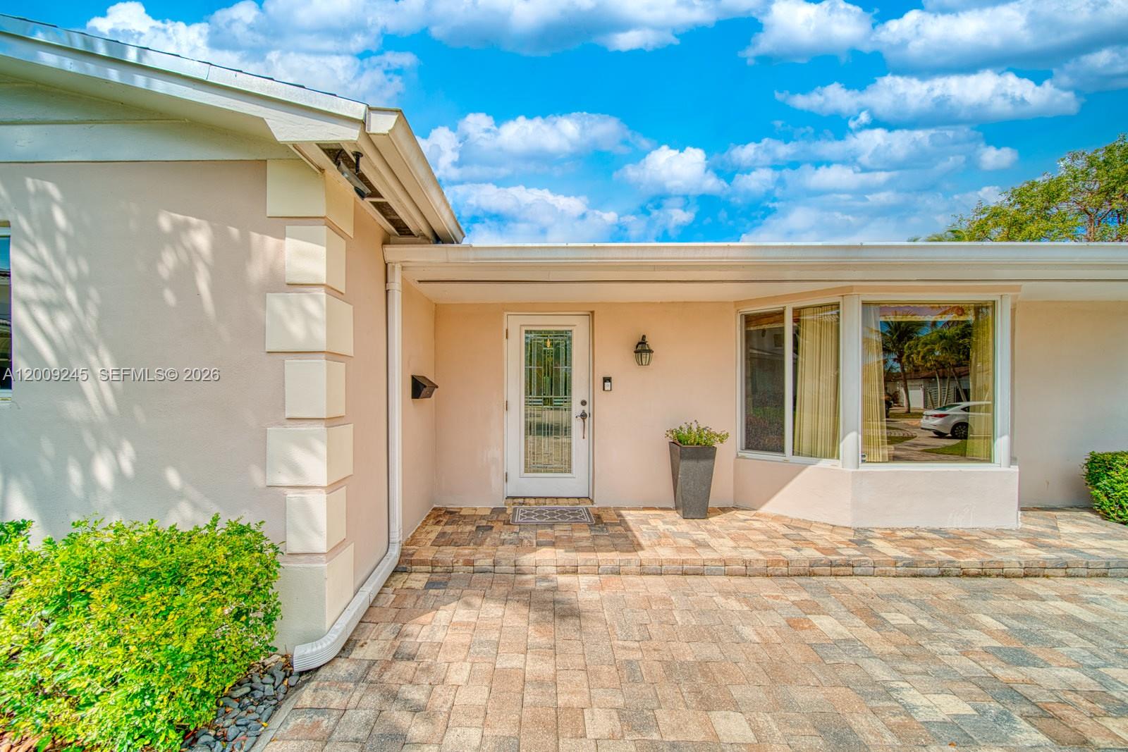 The exterior view shows a beige house with a brick-paved entryway and bay window — 10641 SW 99th Ter, Miami FL 33176, MIAMI, FL