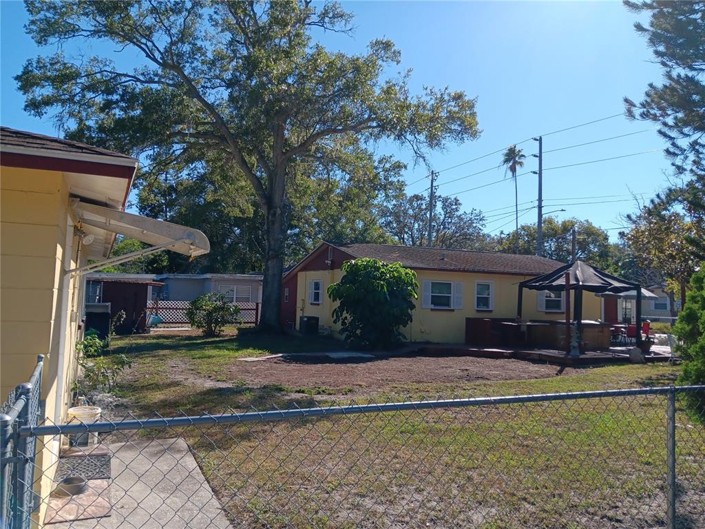 A backyard view showing a yellow house, a gazebo, and a large tree — 374 3RD STREET NW, LARGO, FL