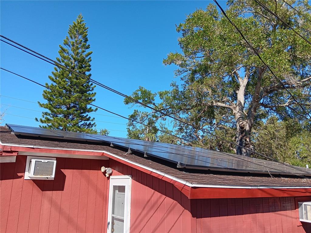 A red house exterior features a roof covered with solar panels under a clear sky — 374 3RD STREET NW, LARGO, FL