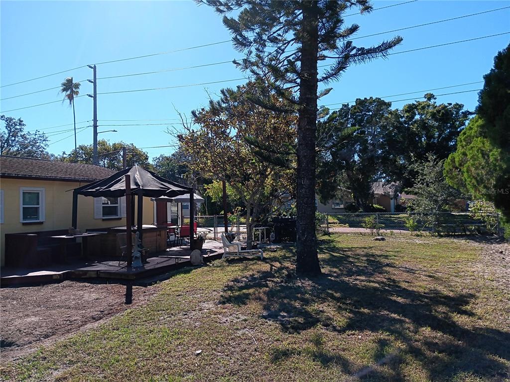 A backyard features a wooden deck with a gazebo, a hot tub, and mature trees — 374 3RD STREET NW, LARGO, FL