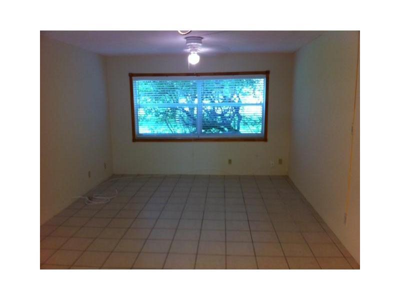 An empty room features light-colored tile flooring, beige walls, and a large window with blinds — 4165 SW 67th Avenue # 107b, Davie FL 33314, DAVIE, FL
