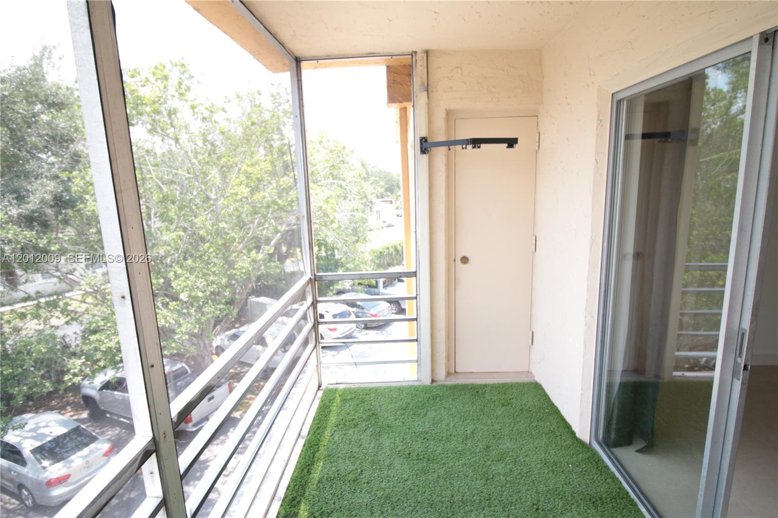A screened-in balcony features artificial turf flooring, a storage closet, and a metal railing — 4314 NW 9th Ave # 3C, Deerfield Beach FL 33064, DEERFIELD BEACH, FL