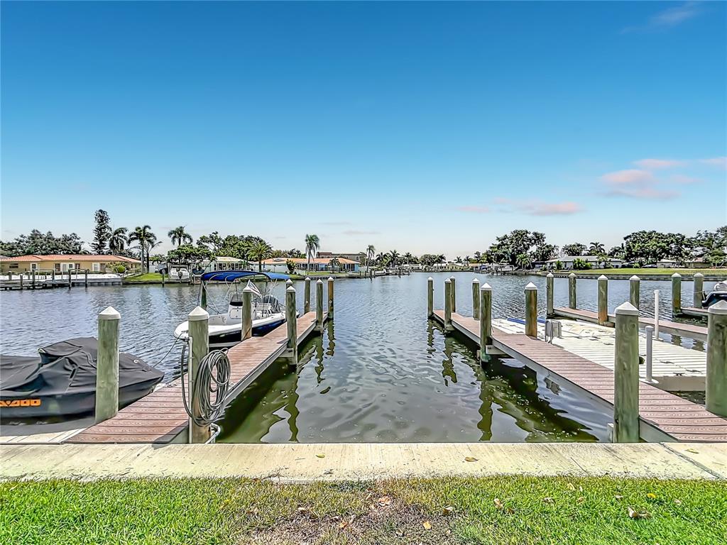 A view of a canal with two wooden boat docks and a small motorboat — 6537 CAPE HATTERAS WAY NE UNIT 2, ST PETERSBURG, FL