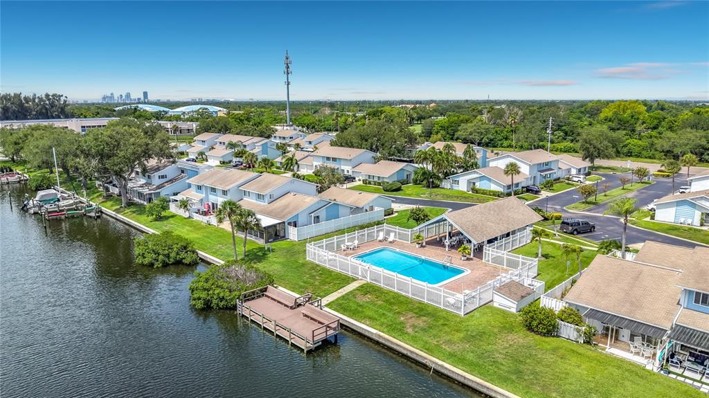 An aerial view of a waterfront residential complex featuring a swimming pool and boat docks — 6537 CAPE HATTERAS WAY NE UNIT 2, ST PETERSBURG, FL