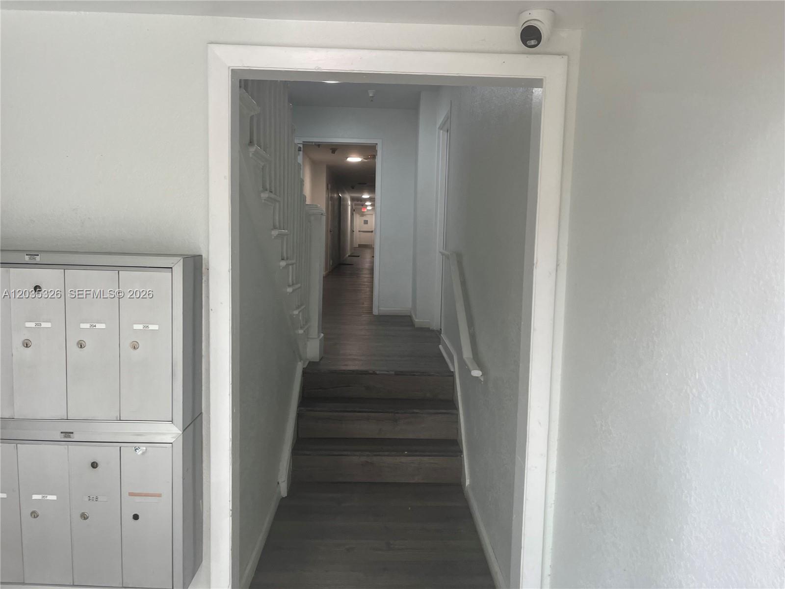A hallway with stairs leads to a corridor, featuring mailboxes on the left wall — 1550 Drexel Ave # 203, Miami Beach FL 33139, MIAMI BEACH, FL