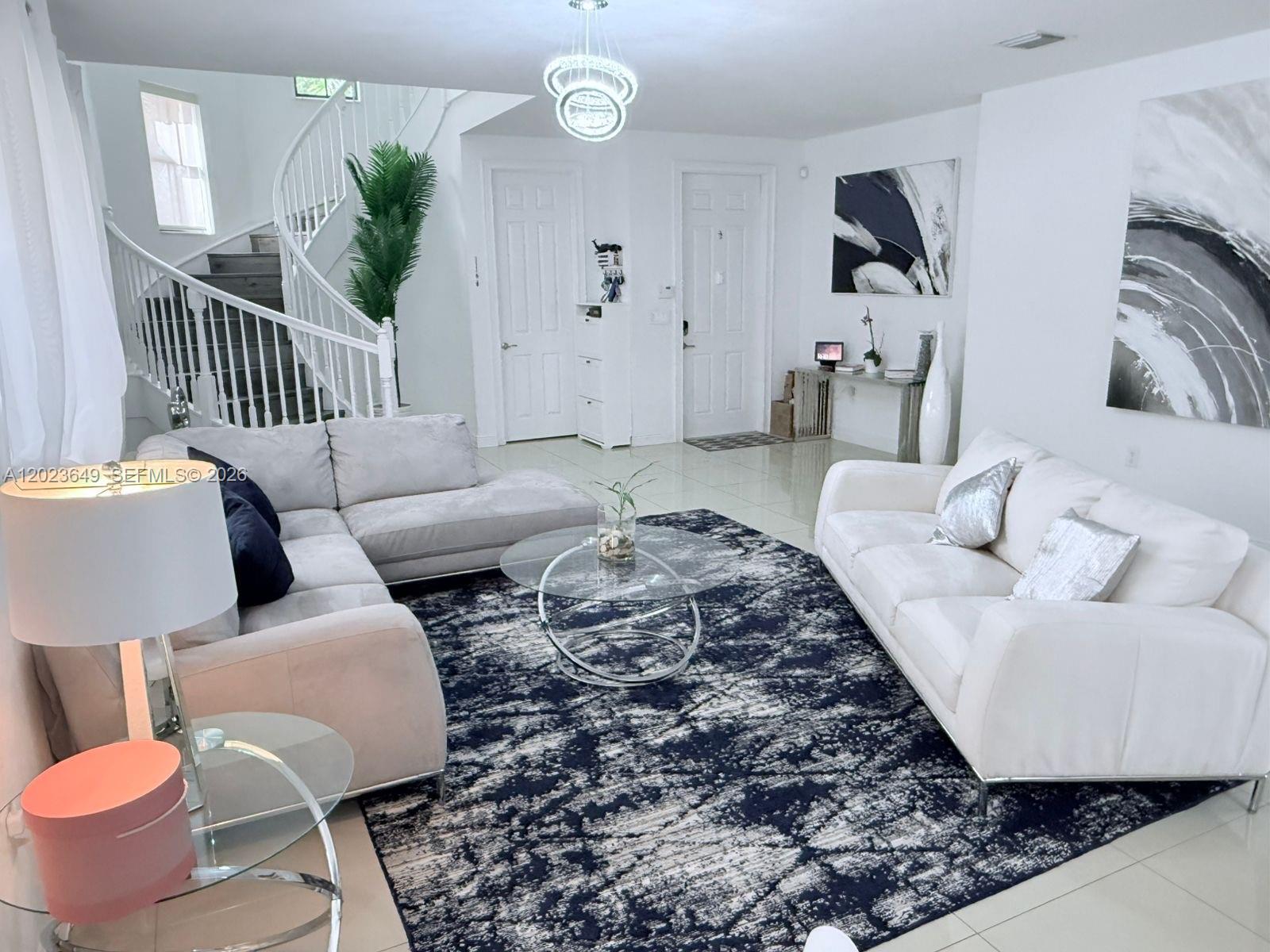 A living room features a white sectional sofa, a glass coffee table, and a spiral staircase — 9907 NW 87th Ter, Doral FL 33178, DORAL, FL