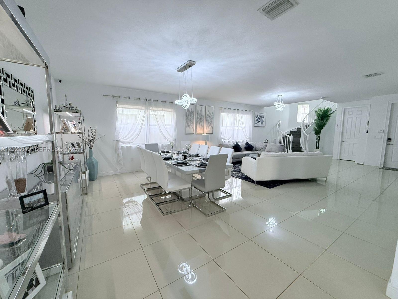 A bright, open-concept living and dining area features white tile floors and modern furniture — 9907 NW 87th Ter, Doral FL 33178, DORAL, FL