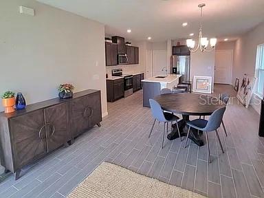 An open-concept dining area and kitchen feature dark wood cabinetry, gray tile flooring, and furniture — 1316 MIRABELLA CIRCLE, DAVENPORT, FL