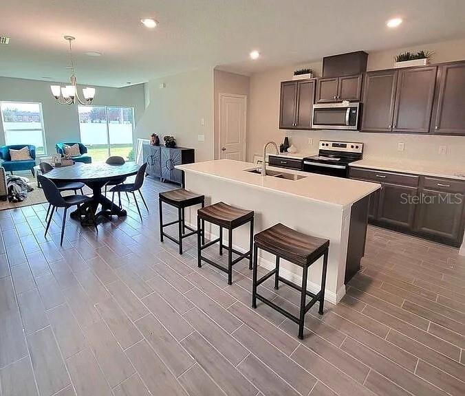 A kitchen features dark cabinetry, a central island with three stools, and an adjacent dining area — 1316 MIRABELLA CIRCLE, DAVENPORT, FL