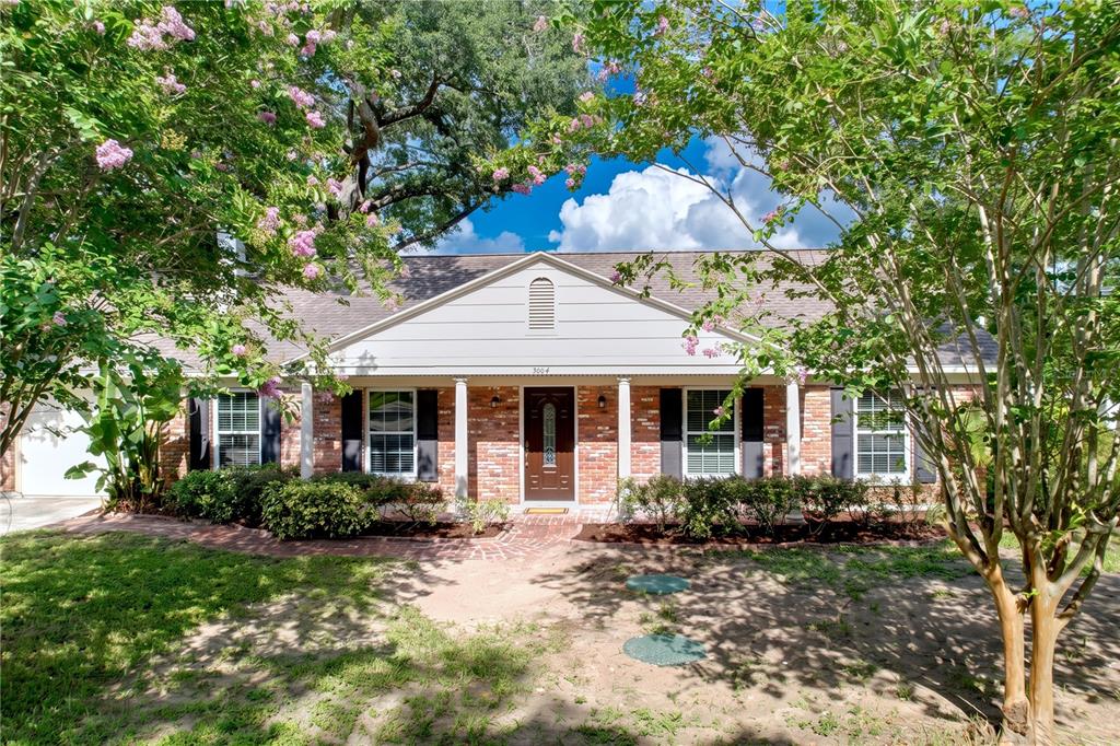 A single-story brick house with a front porch, white columns, and blooming crape myrtle trees — 3604 MARCO DRIVE, TAMPA, FL