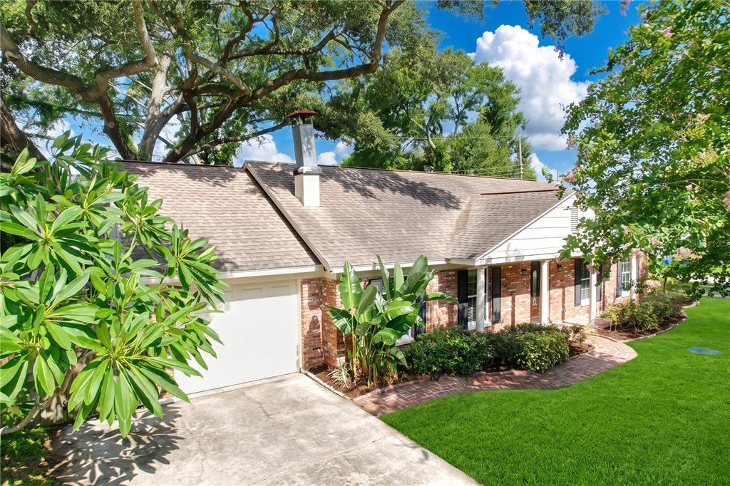 A single-story brick house with a white garage door, shingled roof, and mature trees — 3604 MARCO DRIVE, TAMPA, FL
