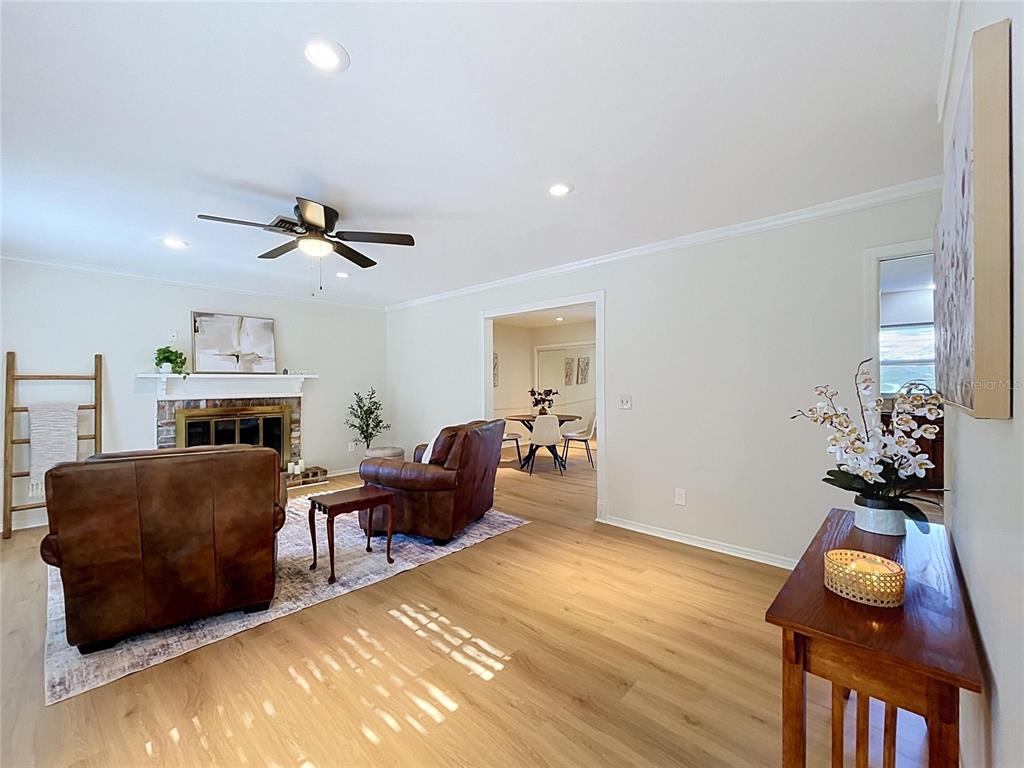 A living room features leather armchairs, a brick fireplace, and light wood-look flooring — 3604 MARCO DRIVE, TAMPA, FL