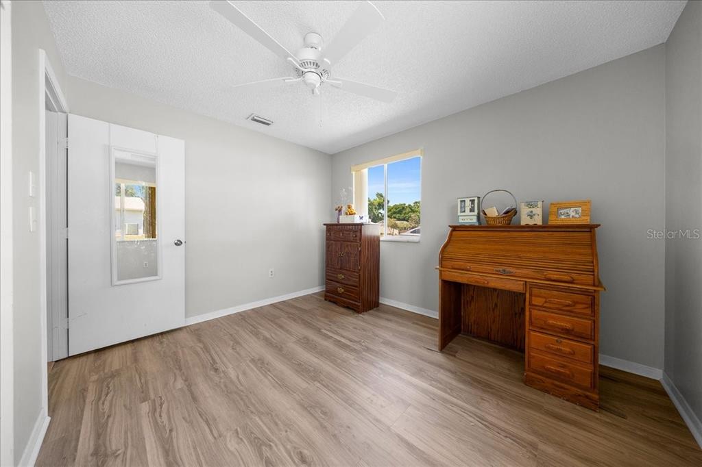 A bedroom with light gray walls, wood-look flooring, a ceiling fan, and wooden furniture — 8445 SW 109TH STREET, OCALA, FL