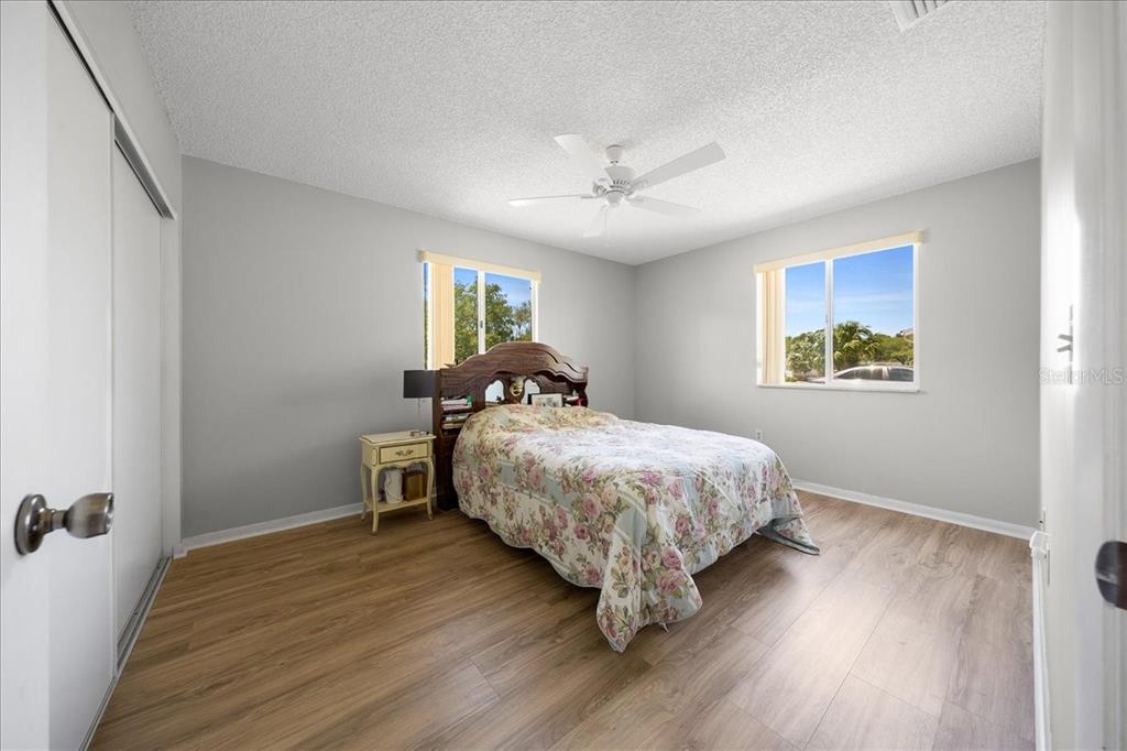 A bedroom with light gray walls, wood-look flooring, a ceiling fan, and a floral bedspread — 8445 SW 109TH STREET, OCALA, FL