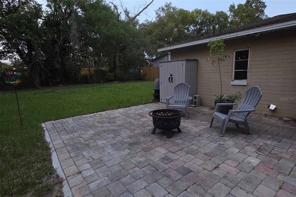 A paved patio with a fire pit and two chairs sits beside a house exterior — 1135 W GREENWOOD STREET, LAKELAND, FL
