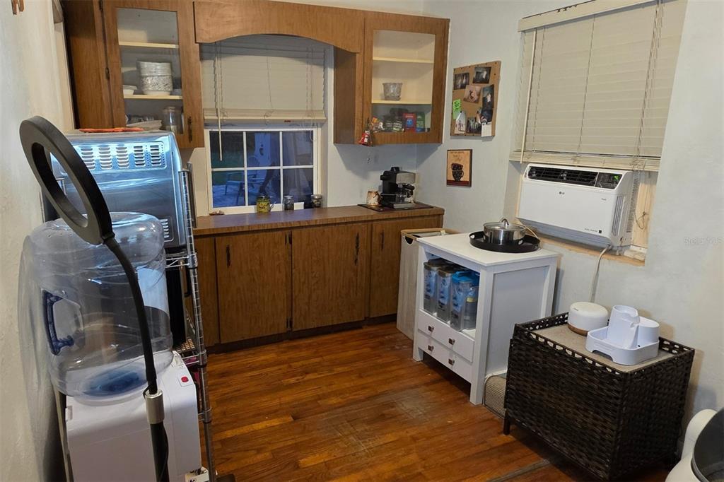 A kitchen features wood cabinets, a window, a white storage cart, and a window air conditioner — 1135 W GREENWOOD STREET, LAKELAND, FL